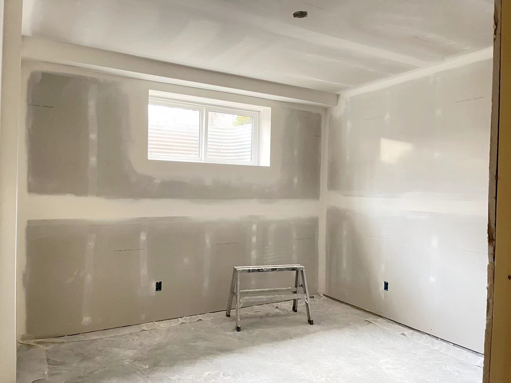 Technicians from ANR Drywall LTD are installing drywall boards in a client's basement.