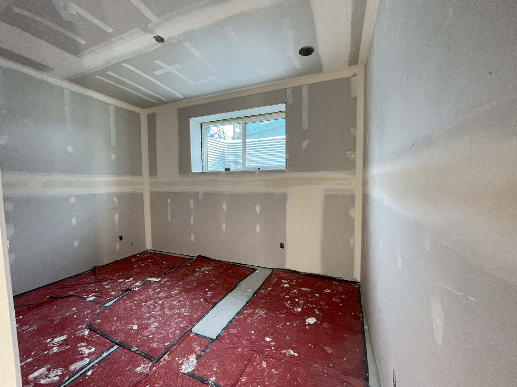 Technicians from ANR Drywall LTD are installing drywall boards in a client's basement.