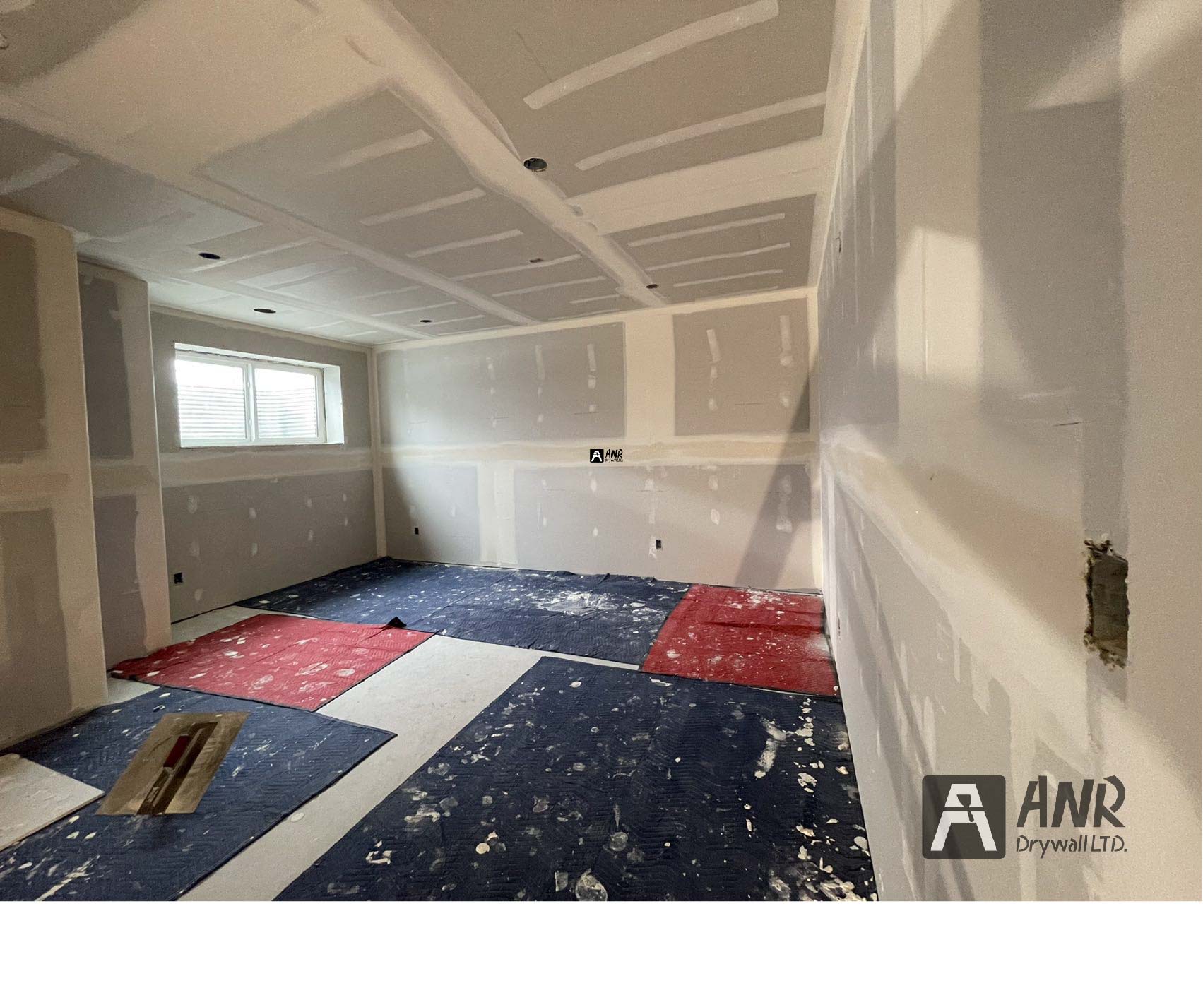 Technicians from ANR Drywall LTD are installing drywall boards in a client's basement.