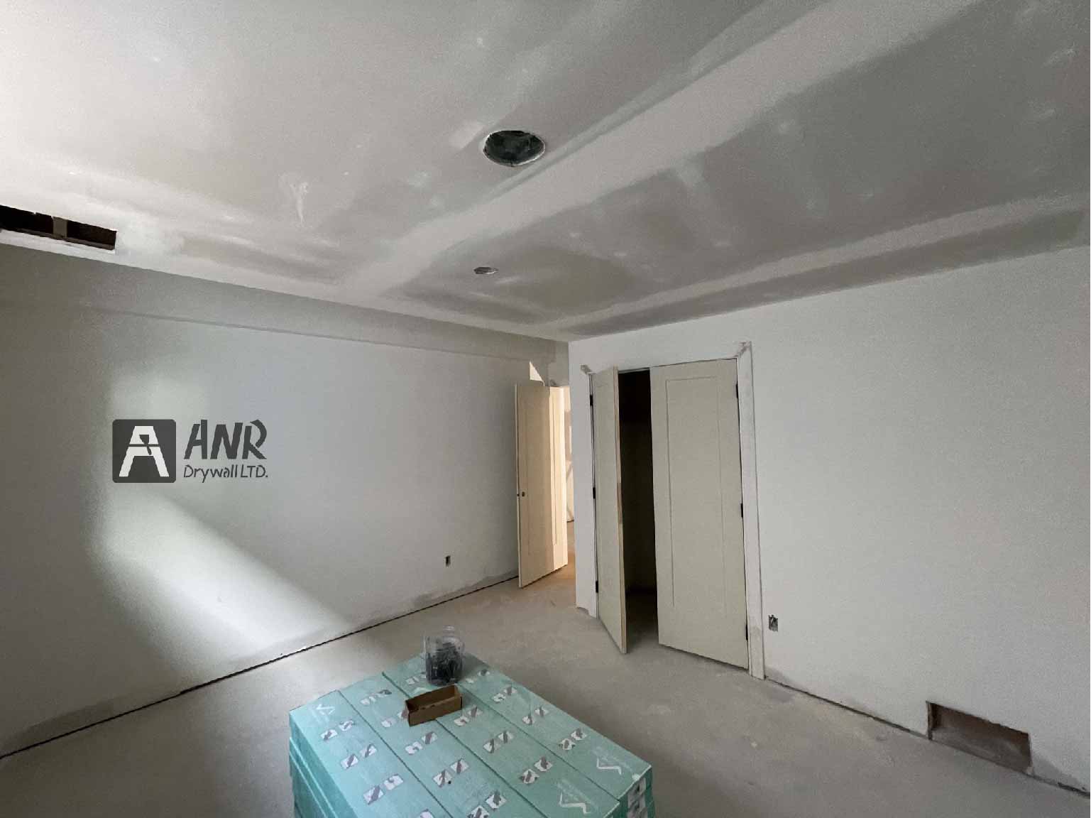 Technicians from ANR Drywall LTD are installing drywall boards in a client's basement.