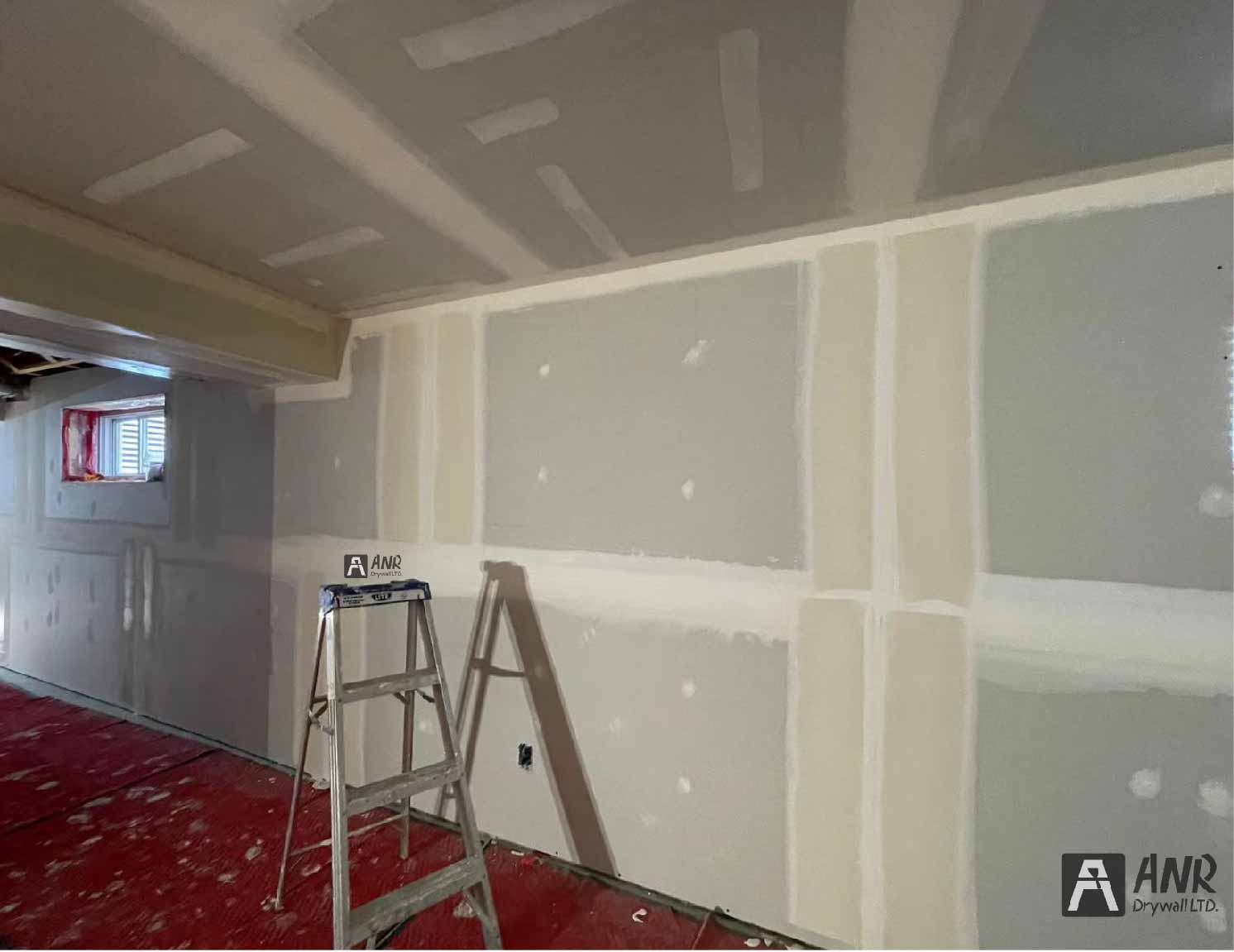 Technicians from ANR Drywall LTD are installing drywall boards in a client's basement.