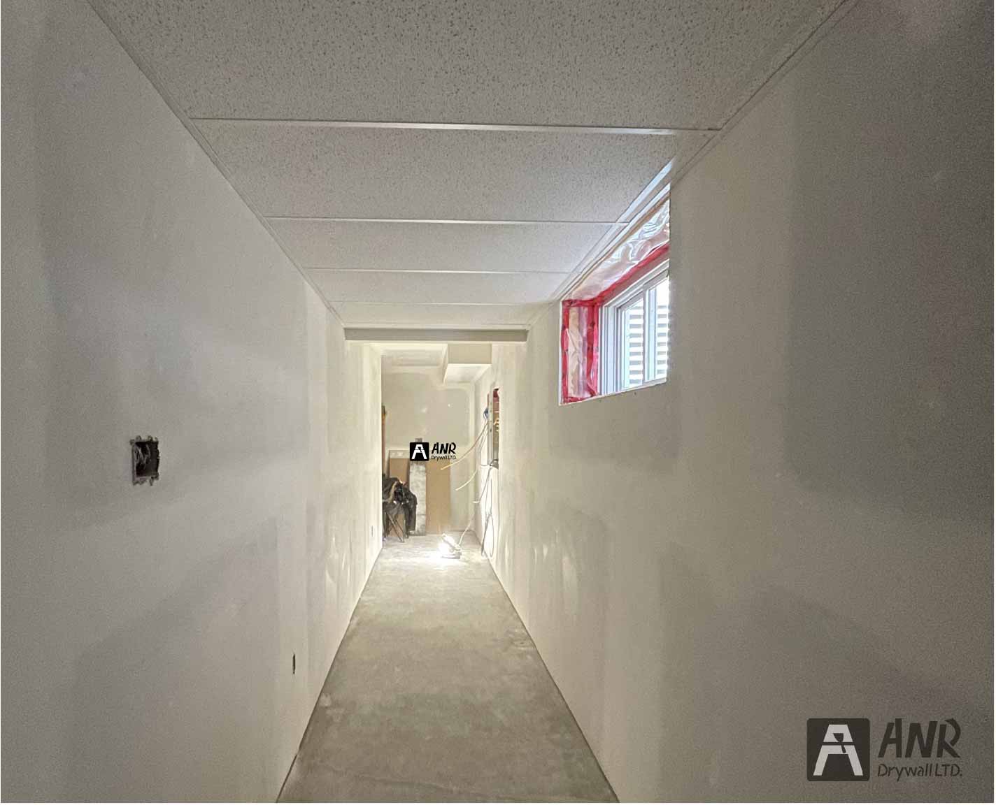 Technicians from ANR Drywall LTD are installing drywall boards in a client's basement.