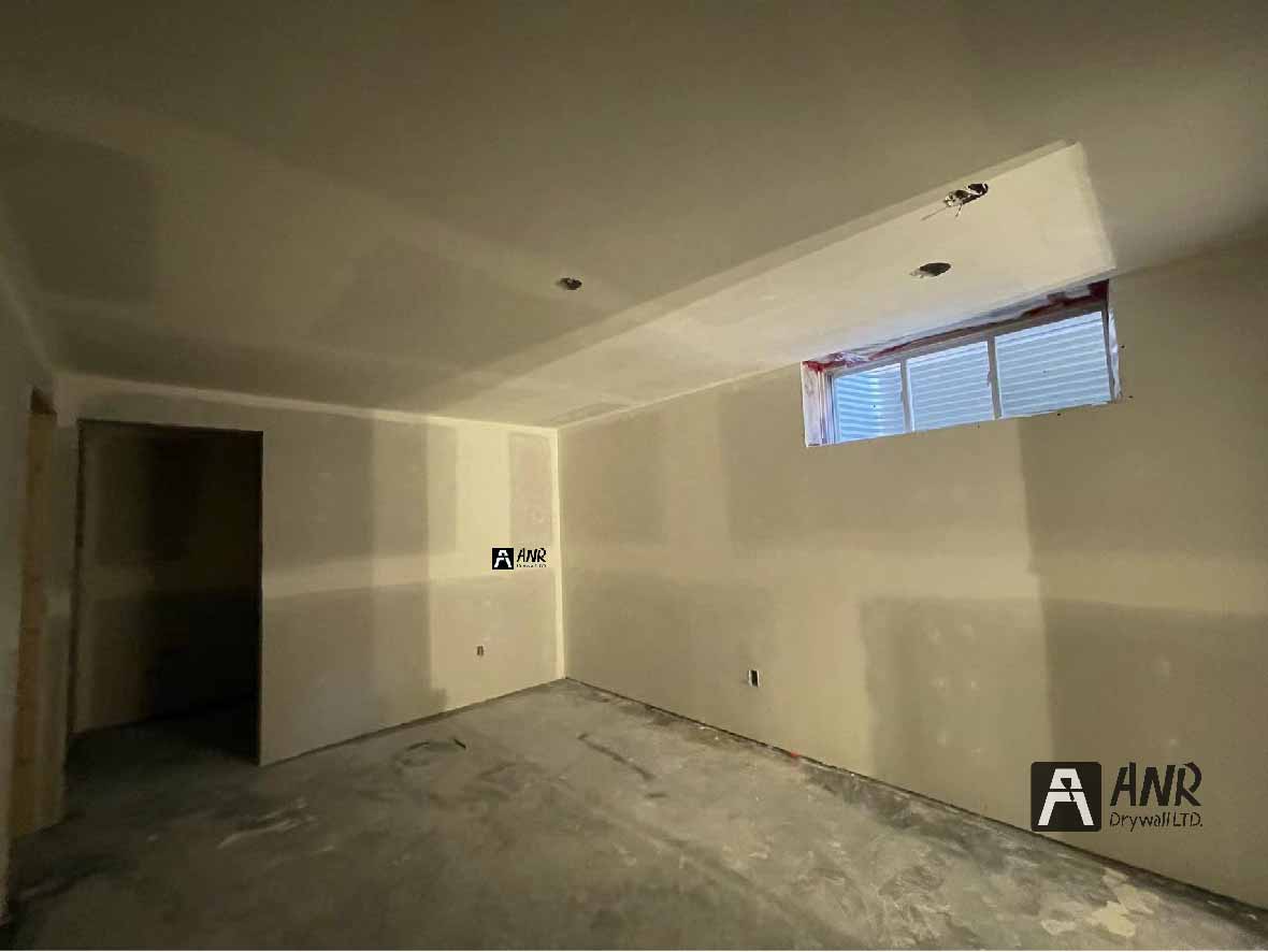 Technicians from ANR Drywall LTD are installing drywall boards in a client's basement.