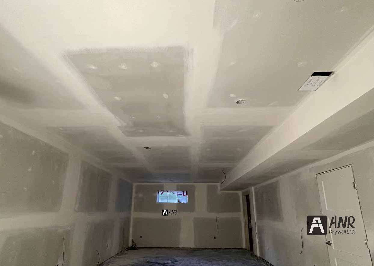 Technicians from ANR Drywall LTD are installing drywall boards in a client's basement.