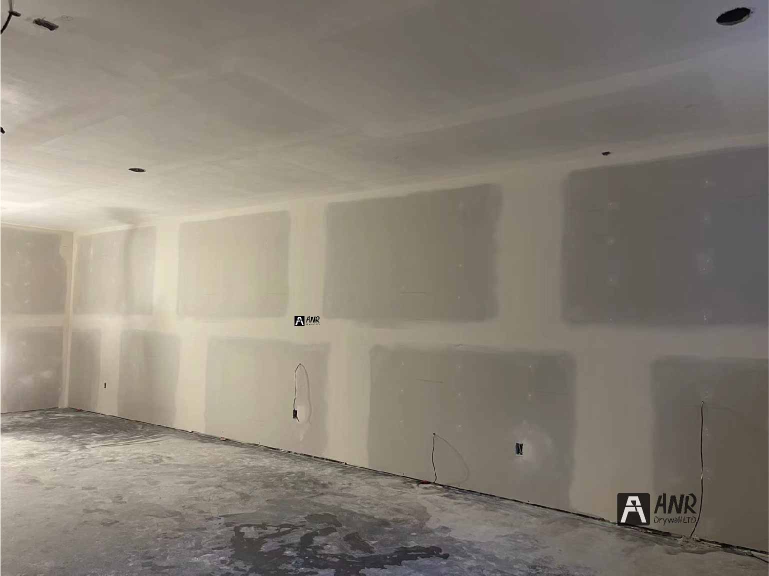 Technicians from ANR Drywall LTD are installing drywall boards in a client's basement.