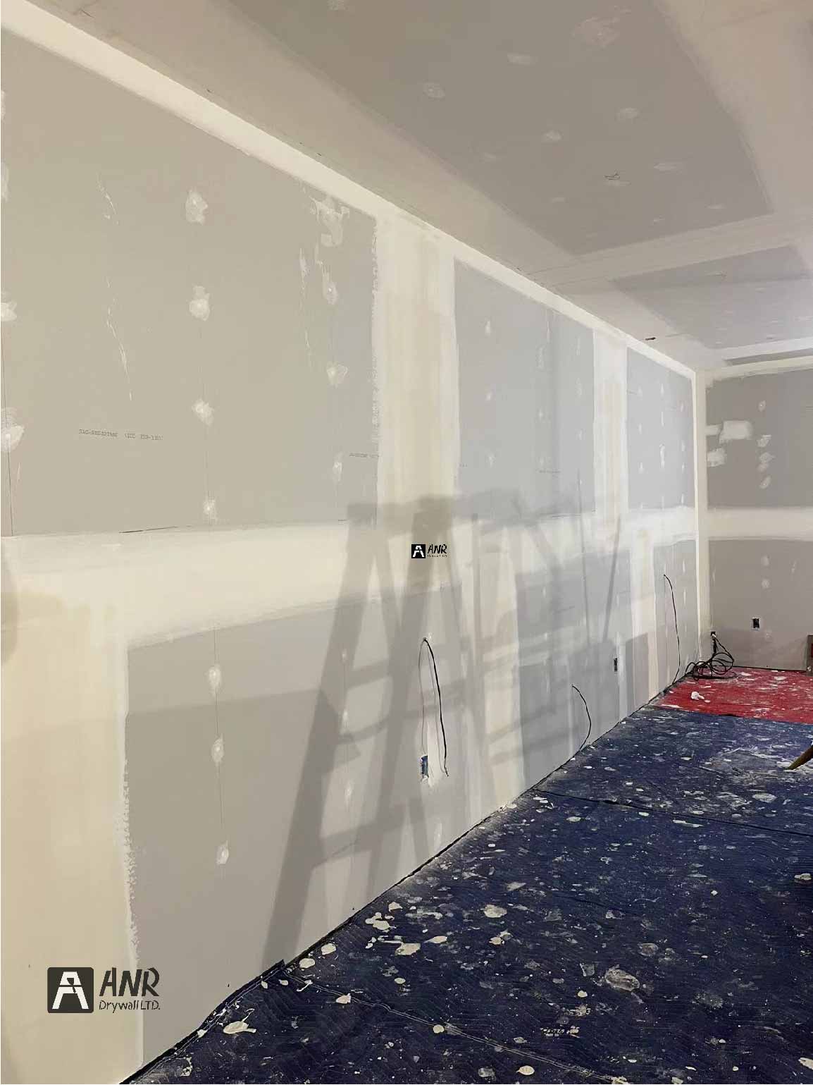 Technicians from ANR Drywall LTD are installing drywall boards in a client's basement.